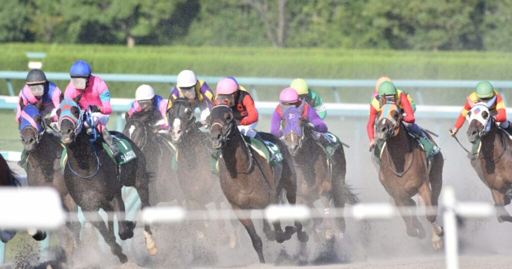 砂煙を上げながら競走する競走馬と騎手たち