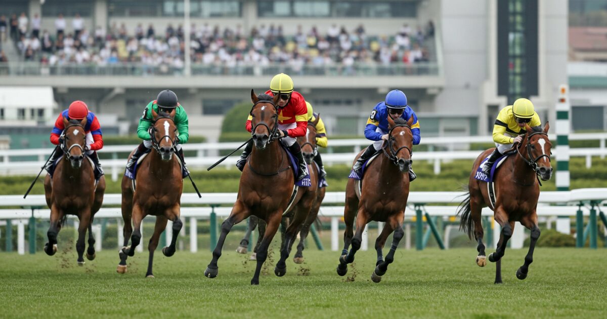 観客席を背景にゴールを目指す競走馬と騎手たち