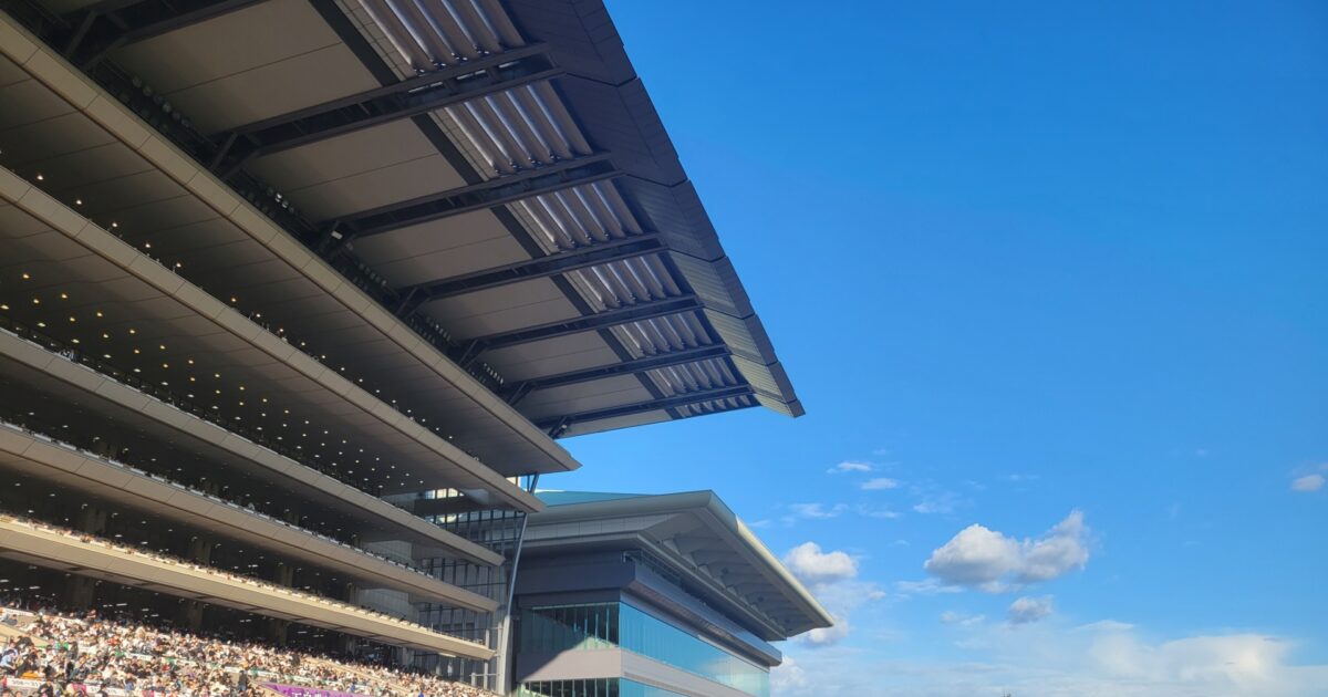 青空とスタンドが美しい競馬場の賑わう観客席